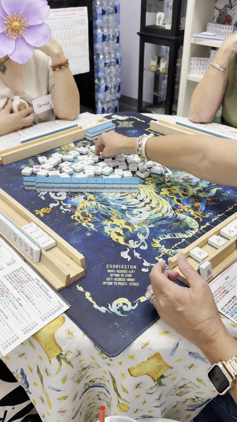 A game with blue-backed tiles; a player’s face covered by a flower